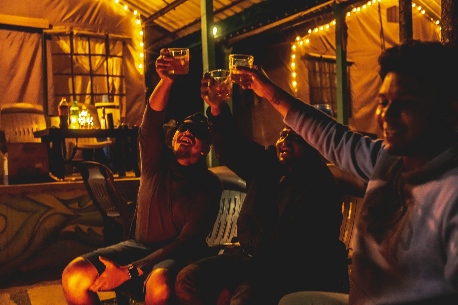 A group of friends raising their drinks together in a warm, low-lit room at night