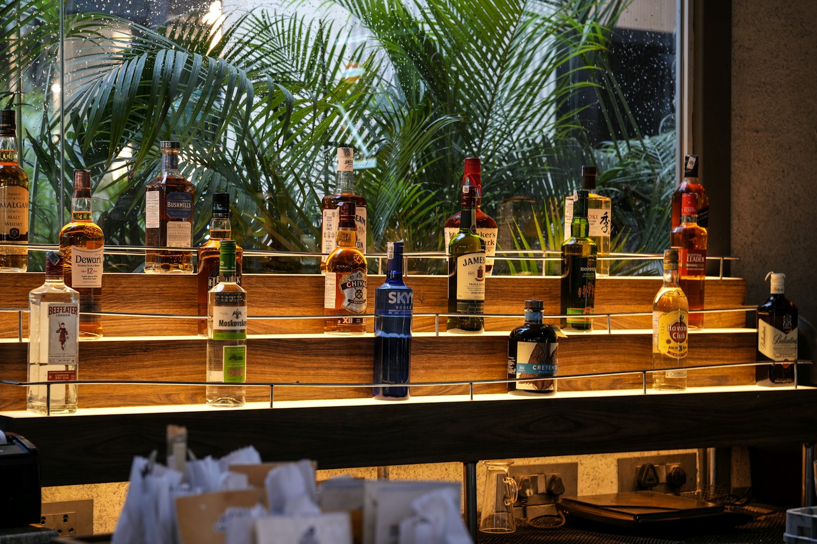Spirit bottles lined up along the warm-lit tiered shelves of a back bar