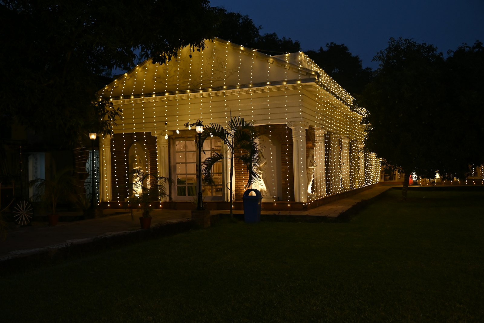 A villa outlined in strings of fairy lights, standing on its lawn after dark
